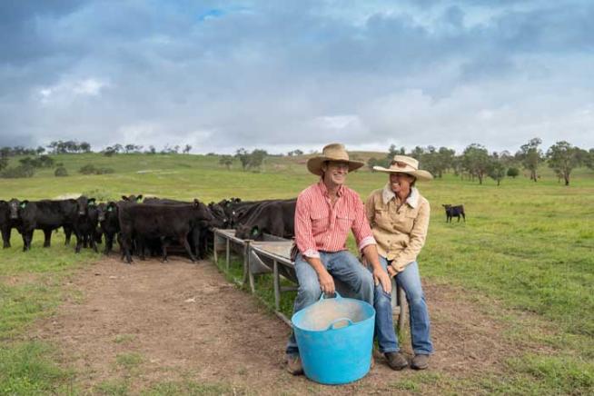 A photo of Stu and Erica Halliday sitting on a cattle feeder